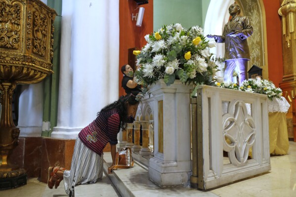 A woman kneels at the shrine dedicated to Dr. Jose Gregorio Hernandez, at a church in Caracas, Venezuela, Tuesday, Feb. 25, 2025, after Pope Francis approved the canonization of the physician known as the 