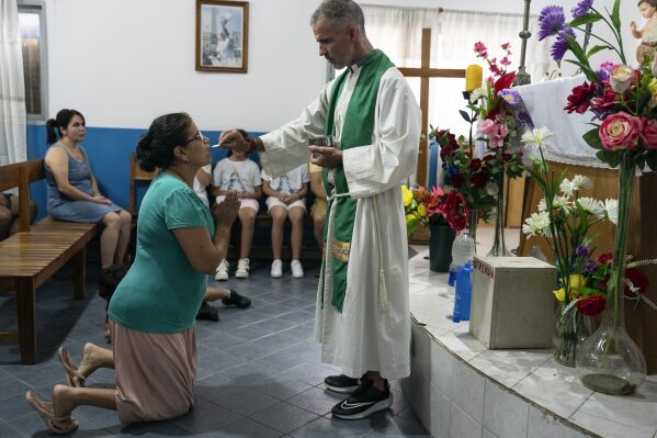 Believers take communion during a Mass for Pope Francis' health at Caacupe church in the Carlos Mugica neighborhood of Buenos Aires, Argentina, Sunday, Feb. 23, 2025. (AP Photo/Rodrigo Abd)