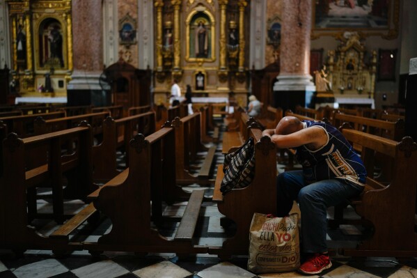 A man bows his head on a pew at San José de Flores basilica, Buenos Aires, Argentina, where Pope Francis worshipped as a youth, Sunday, Feb. 23, 2025. (AP Photo/Natacha Pisarenko)