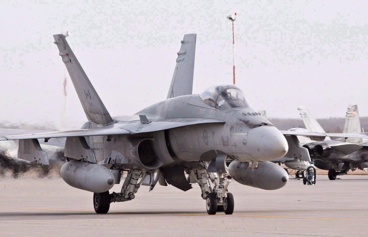 A fighter jet sits on the tarmac. 