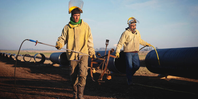 Workers carry equipment during the construction of the Nestor Kirchner gas pipeline.