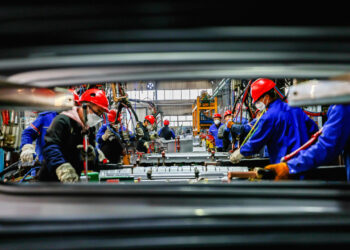 Workers work on the production line at the production workshop of Qingdao Wushun Auto Mold Parts Co. LTD. in China.
