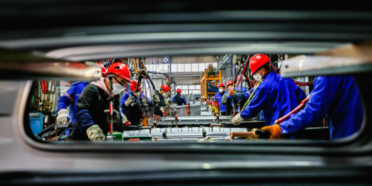 Workers work on the production line at the production workshop of Qingdao Wushun Auto Mold Parts Co. LTD. in China.