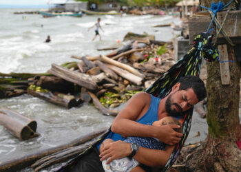 Venezuelan migrant holds his daughter while resting in a hammock