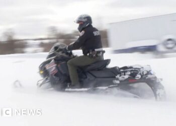 A policeman rides on a snowmobile.