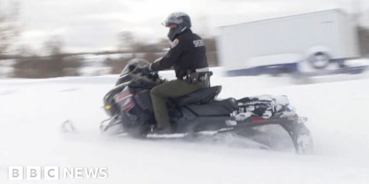 A policeman rides on a snowmobile.