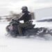A policeman rides on a snowmobile.