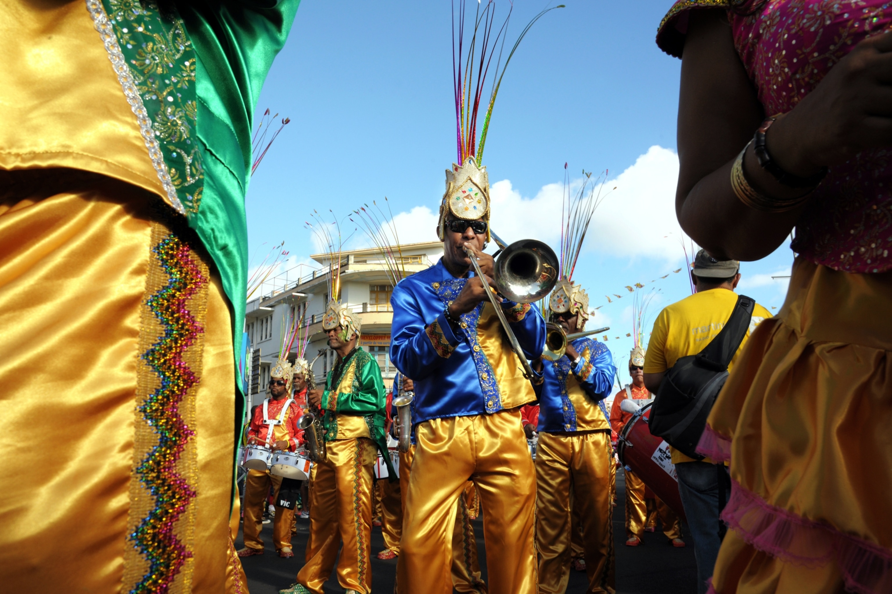 A man performs while surrounded by others in yellow garb.