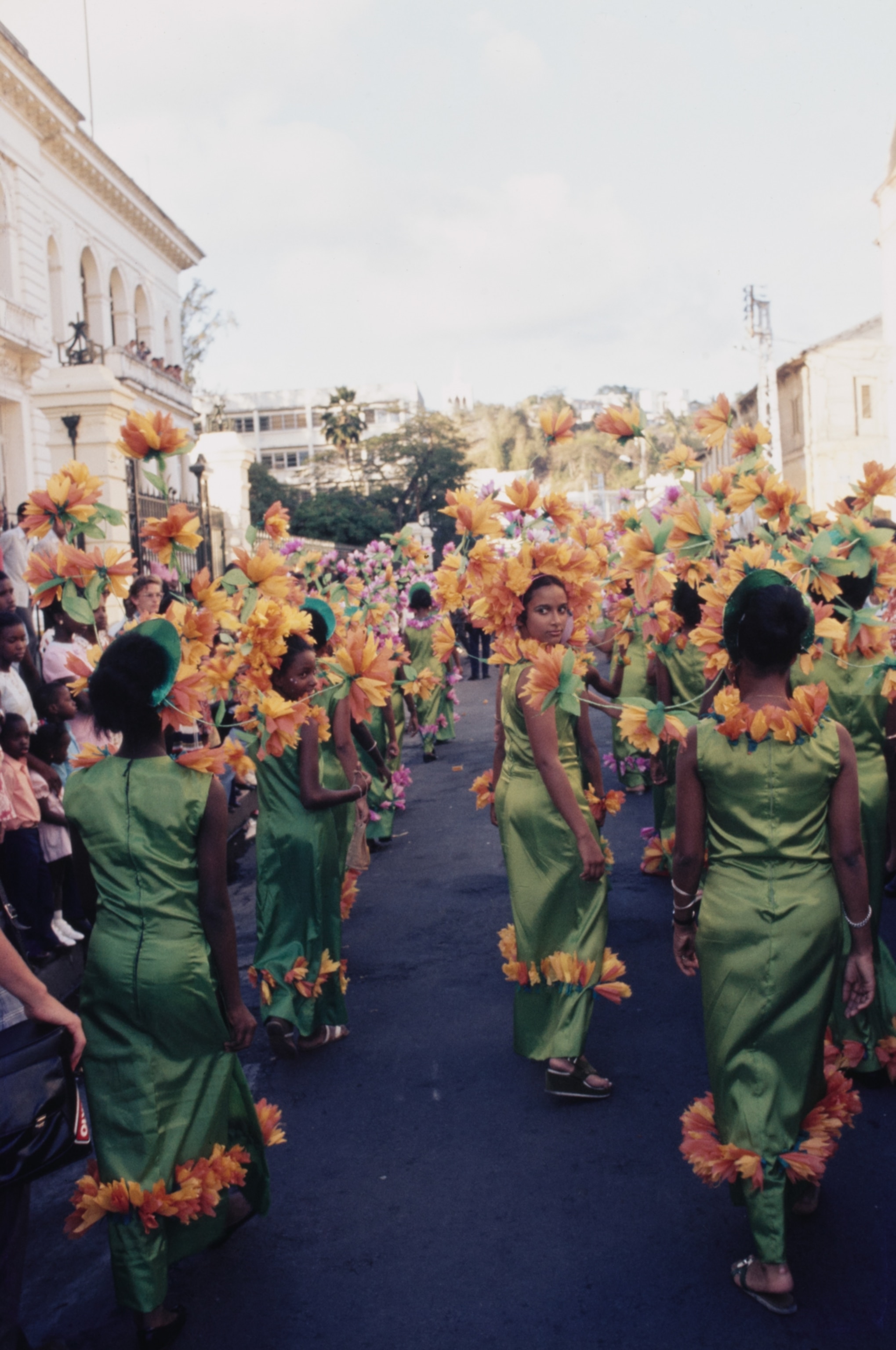 A group of young girls in green and orange one girl looks back at the frame.