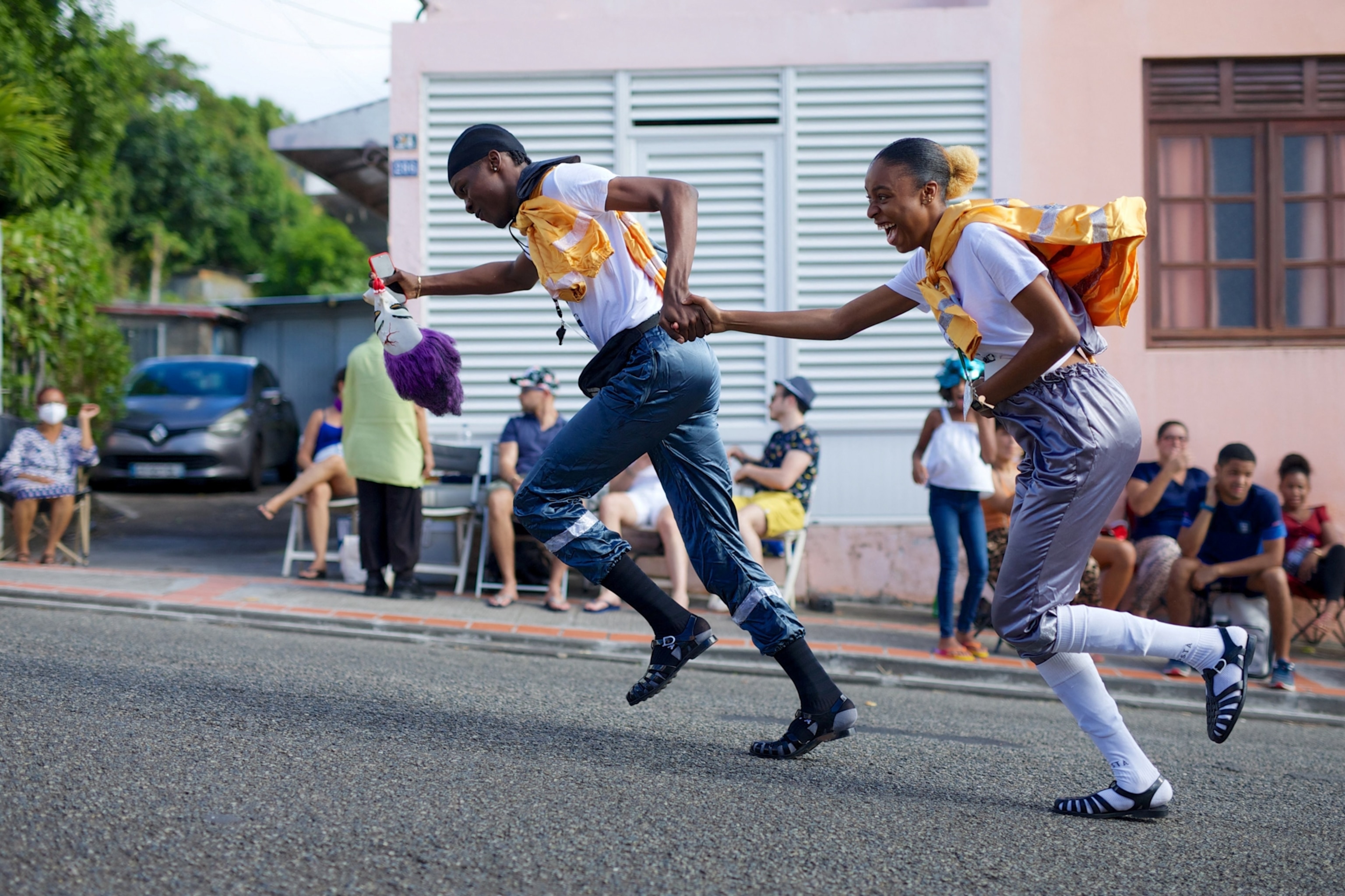A young boy holds a girls hand as they run through through the street .