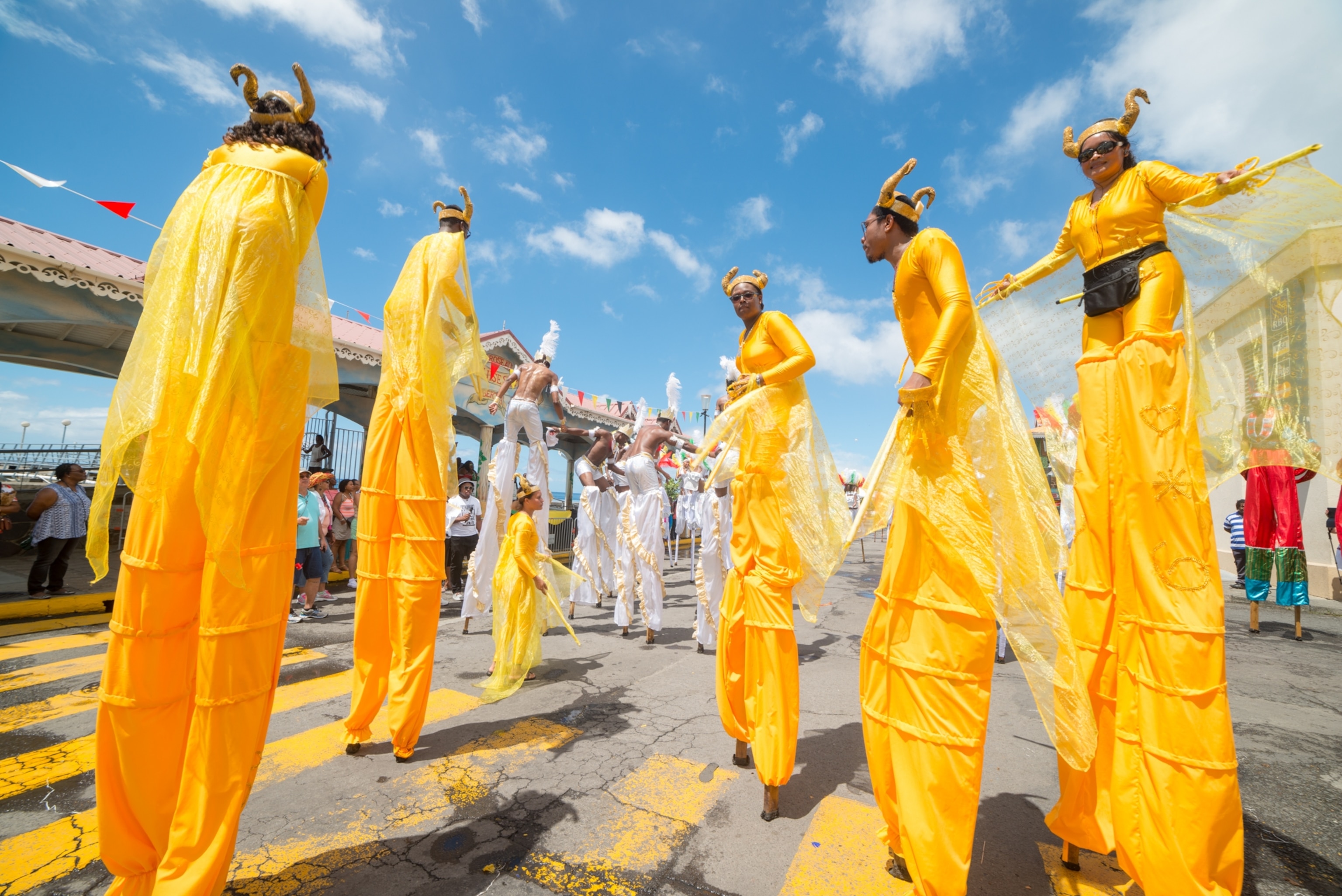 A group of people on stilts in dressed in yellow photographed from below.