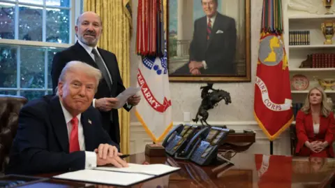 Getty Images U.S. Commerce Secretary Howard Lutnick (2nd-L) speaks as President Donald Trump prepares to sign an executive order in the Oval Office at the White House on February 25, 2025 in Washington, DC. 